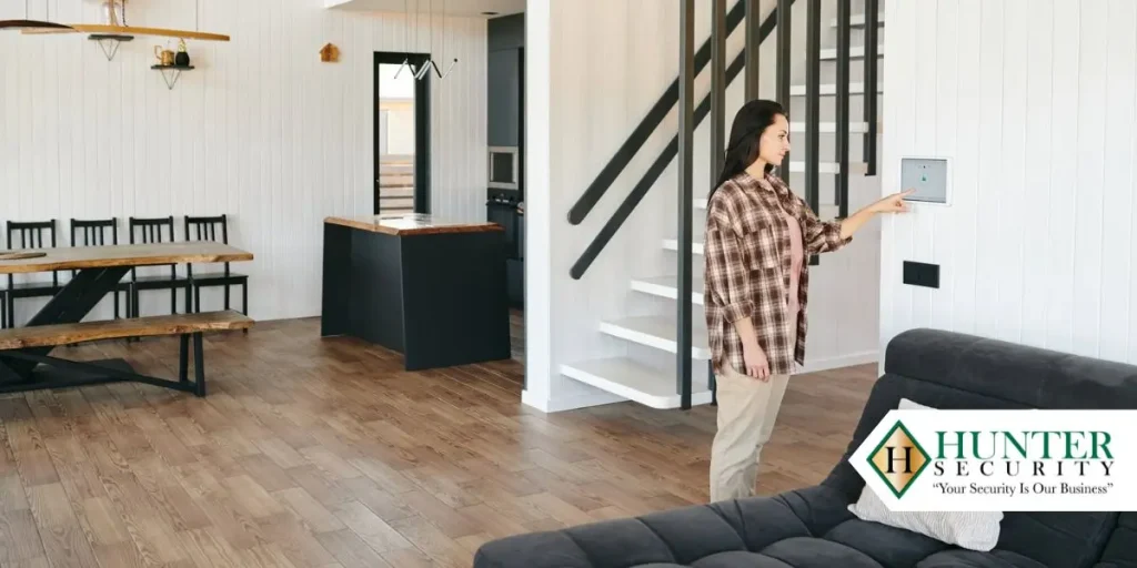 Woman arming a wall-mounted smart security panel in a modern open-plan Alabama home