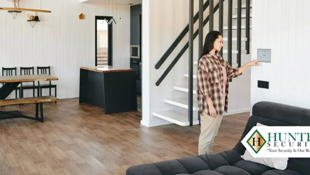 Woman arming a wall-mounted smart security panel in a modern open-plan Alabama home